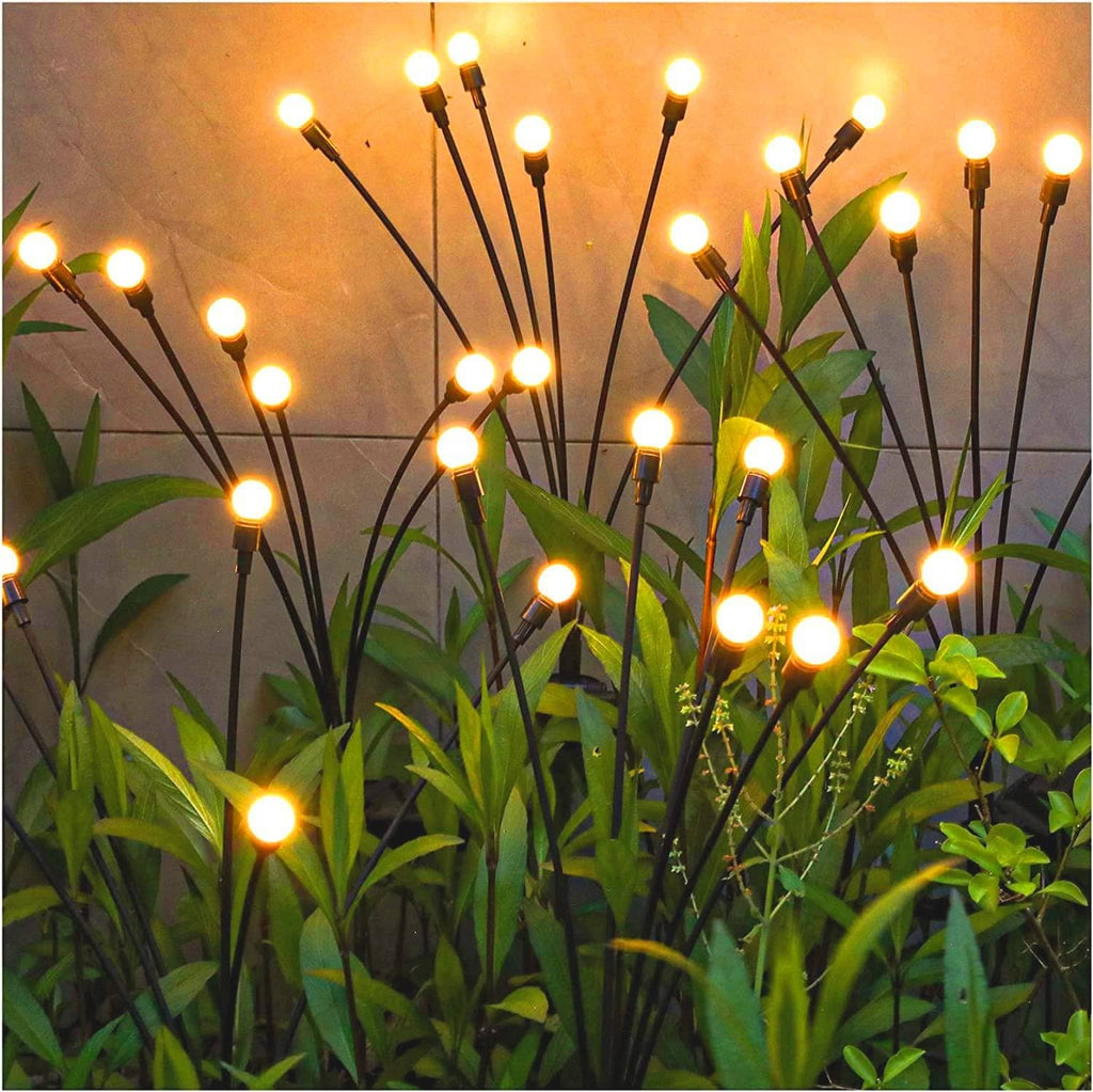 Black solar garden lights with thin swaying stems and warm white glowing bulbs