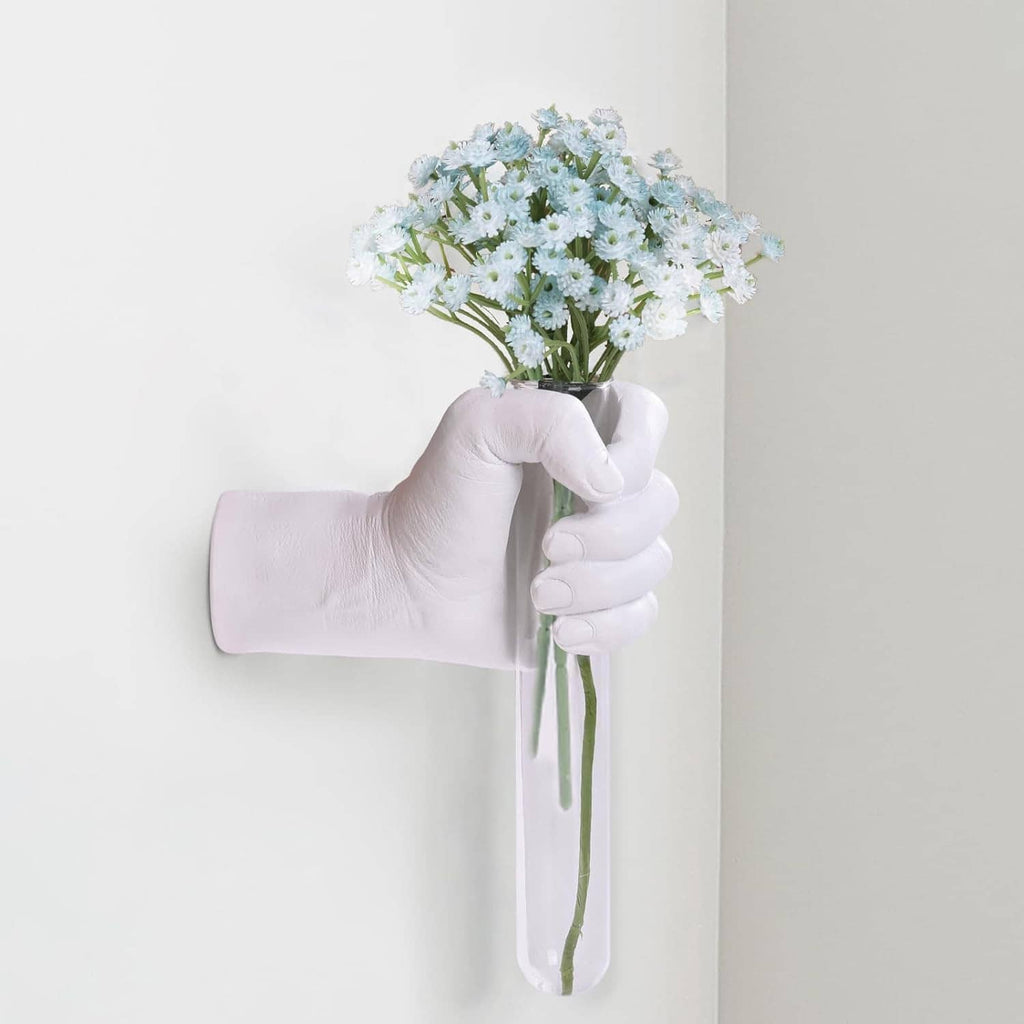 White hand-shaped wall vase with small white daisy bouquet and green stems