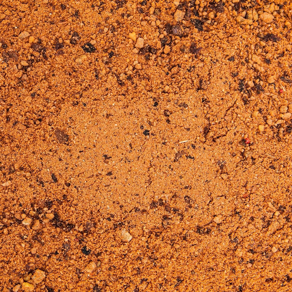 Crushed persimmon deer attractant granules, orange-brown granular texture close-up