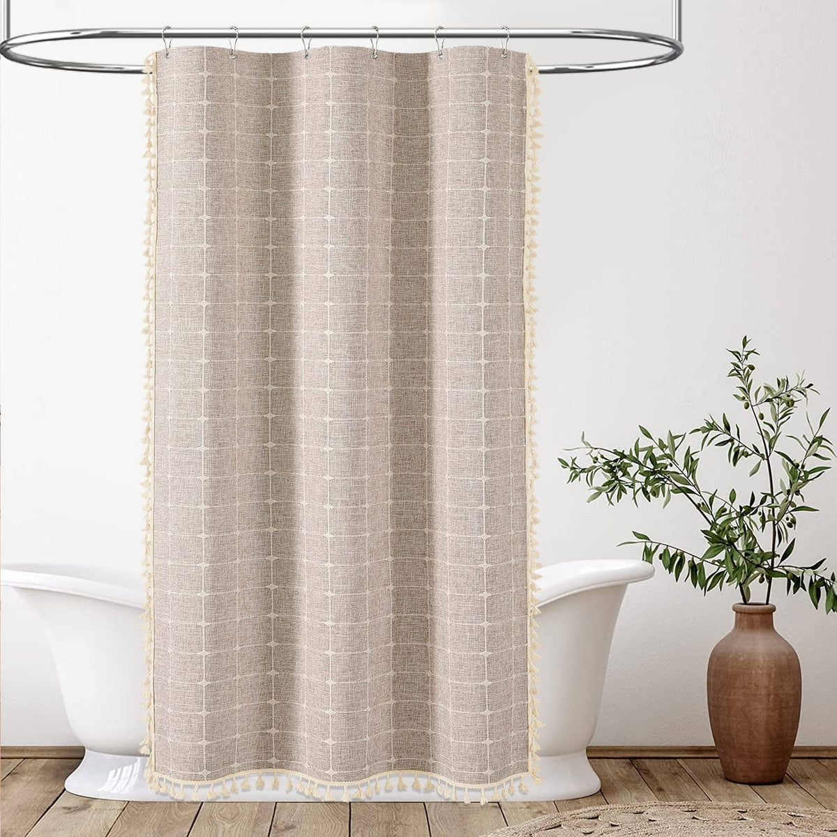 Taupe grid-pattern shower curtain with tassel trim, hanging over bathtub