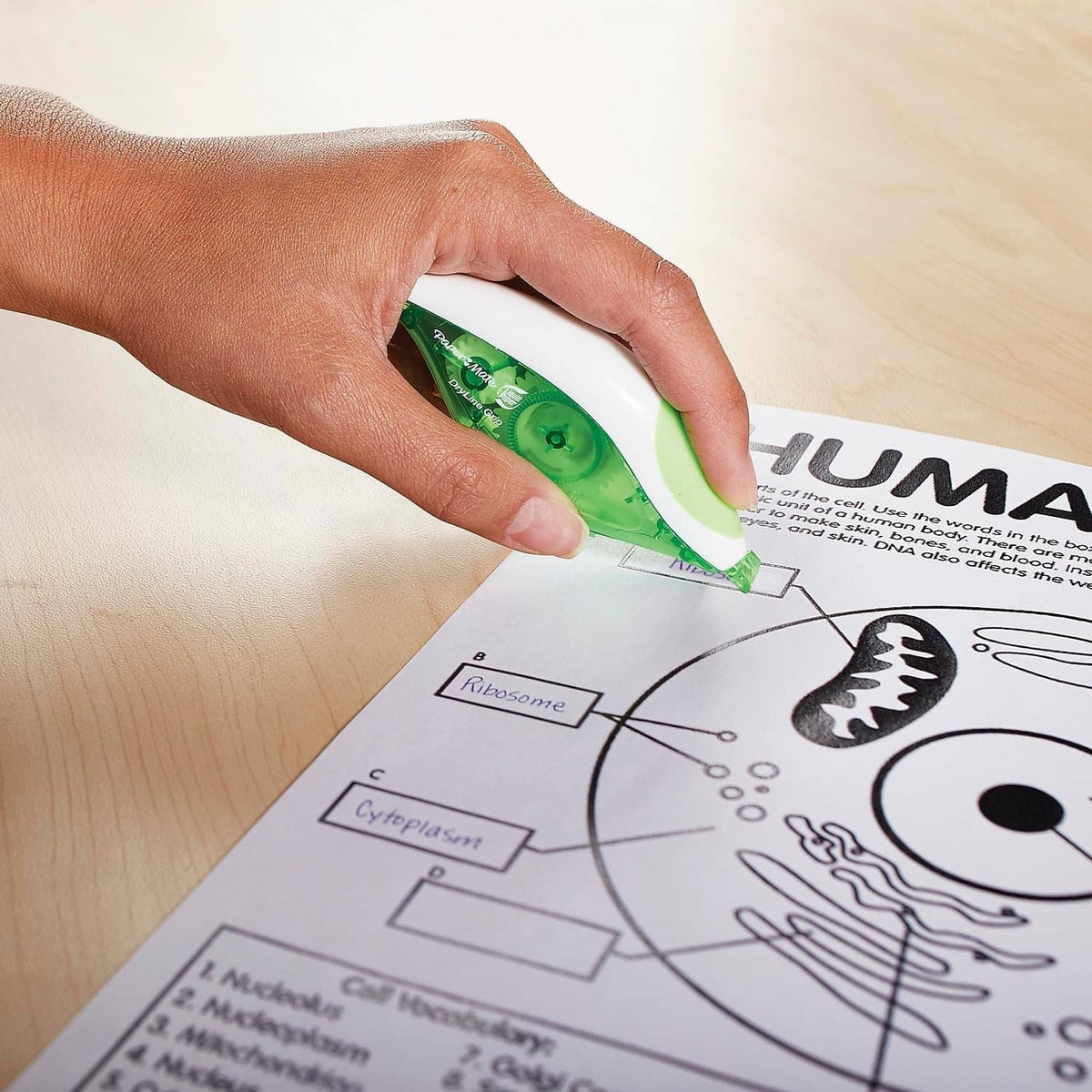 Hand applying green correction tape over a printed chart and diagram