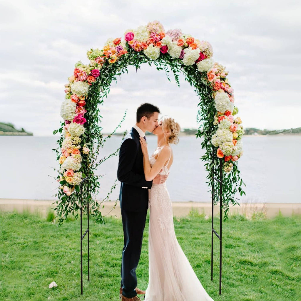 Black-framed floral wedding arch trellis covered with light-colored blossoms