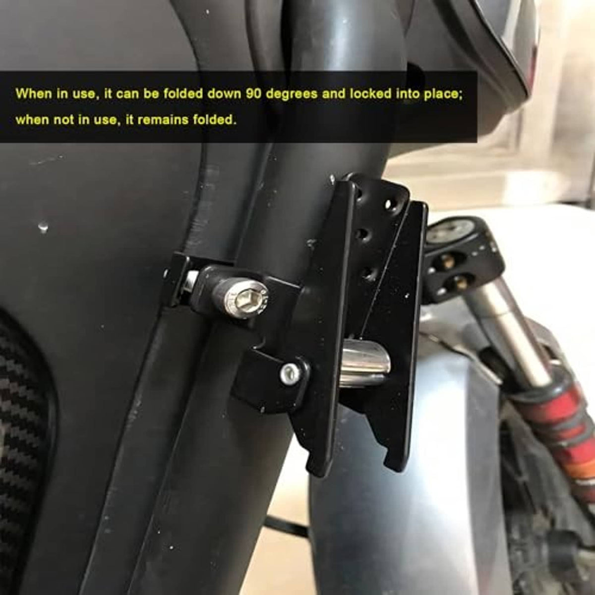 Folded black clamp-on footrest attached to a vehicle frame with visible bolts