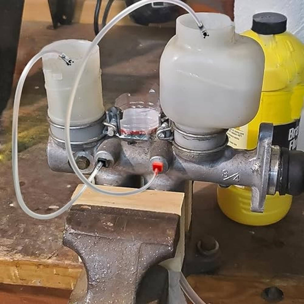 Brake master cylinder bleeder setup with white reservoirs, clear hoses, and connected fittings
