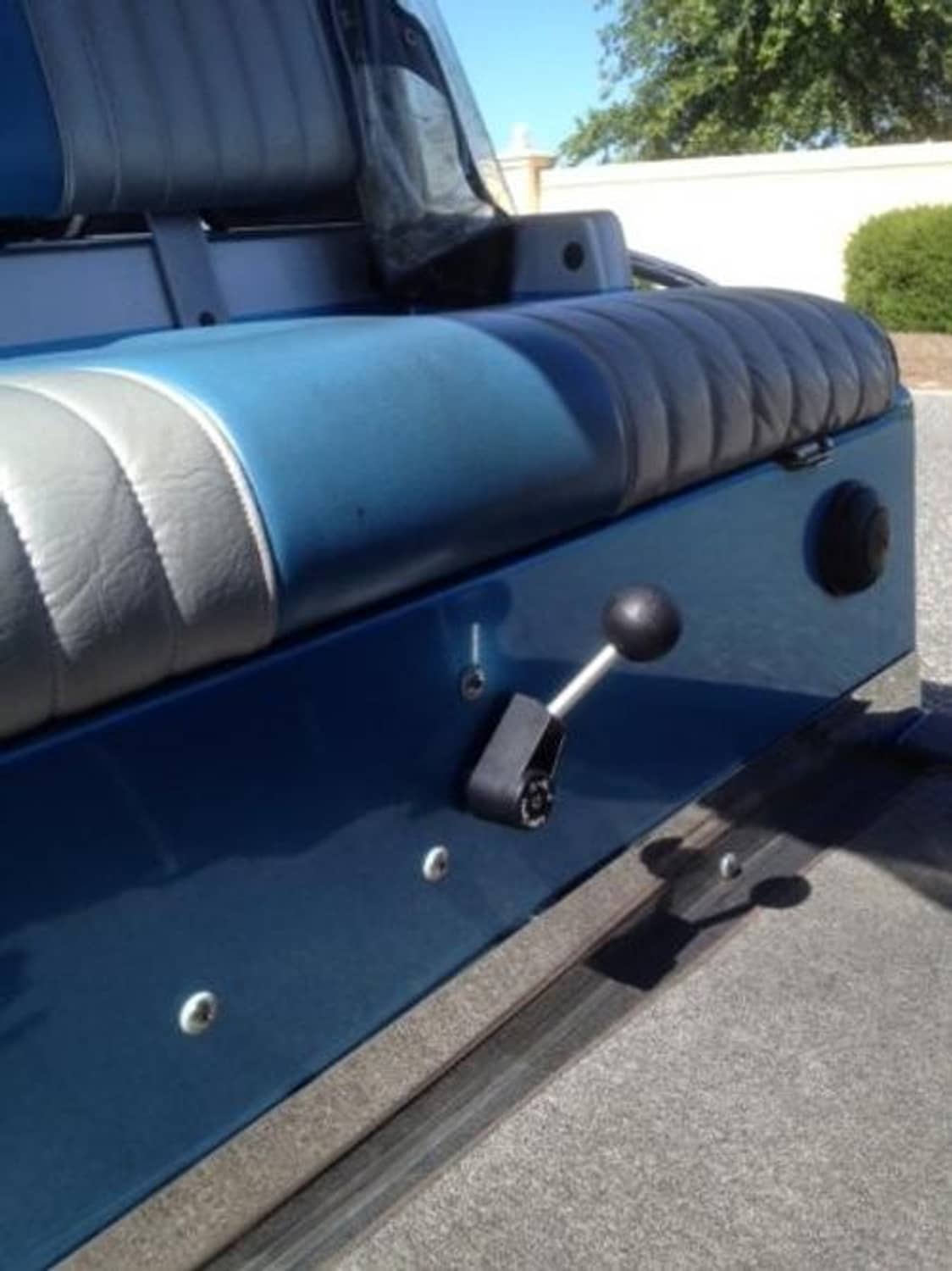 Golf cart shifter lever with round knob mounted near seat on blue cart body