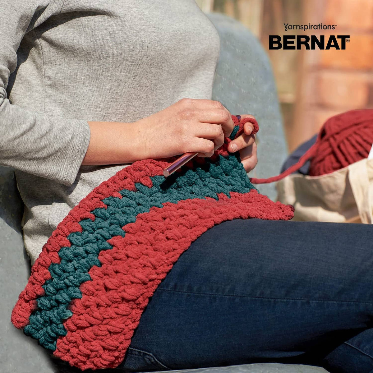 Thick crocheted striped blanket with red and teal-blue zigzag pattern