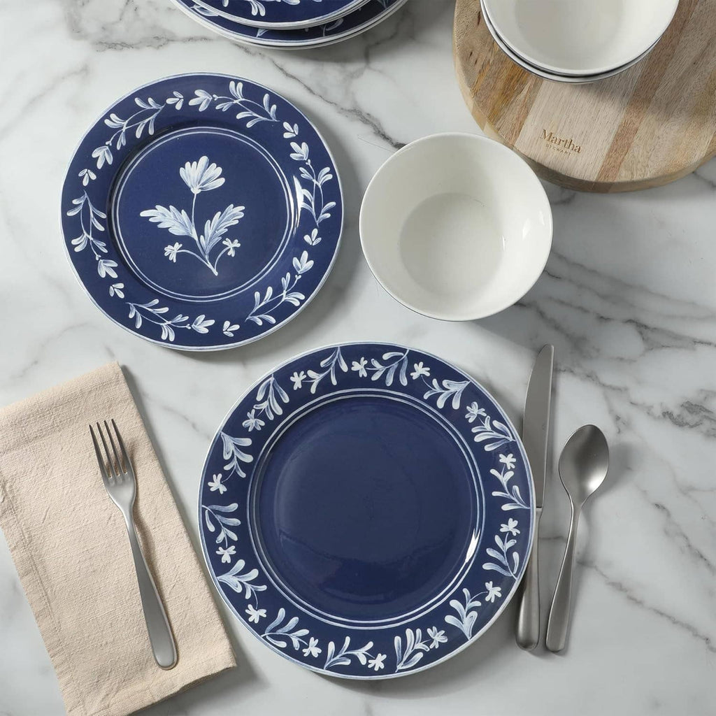 Dark blue floral dinner plates and bowls arranged with utensils and napkin