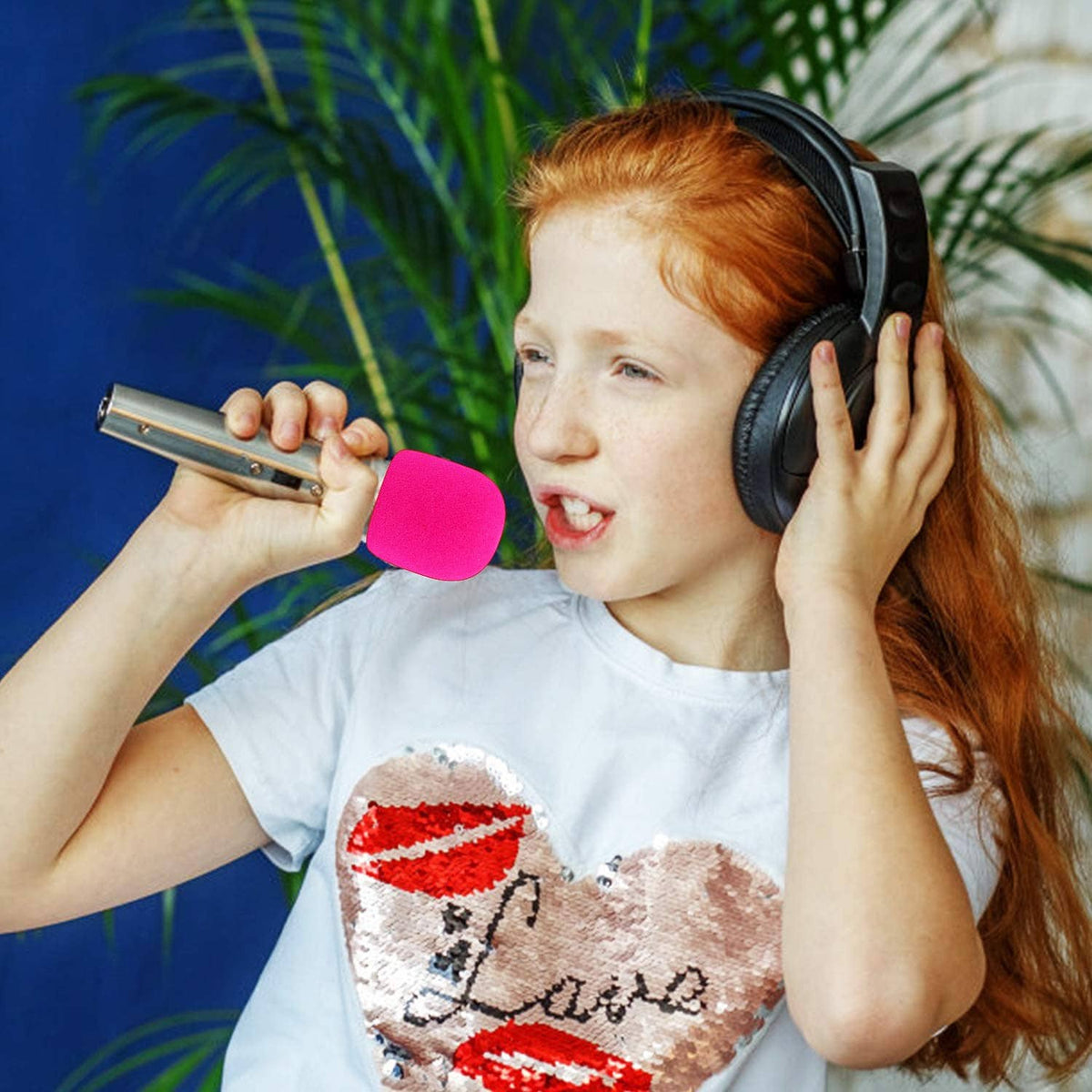 Pink foam microphone windscreen on a handheld microphone near singer
