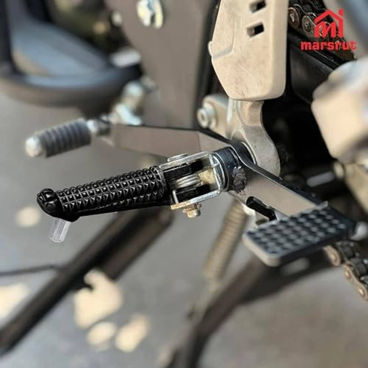 Front foot peg with textured black grip and metal mounting hardware