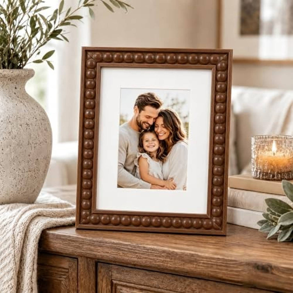 Brown beaded wood picture frame with white mat, standing on a tabletop
