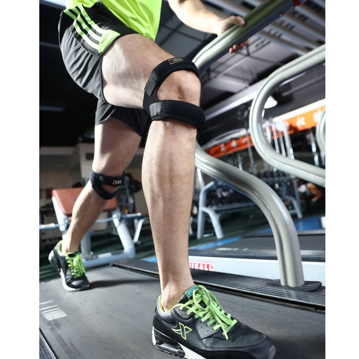 Black dual patella knee strap with teal support worn on a runner’s knee