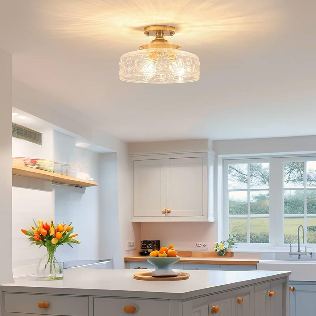 Gold semi-flush ceiling light with clear embossed glass shade centered on ceiling