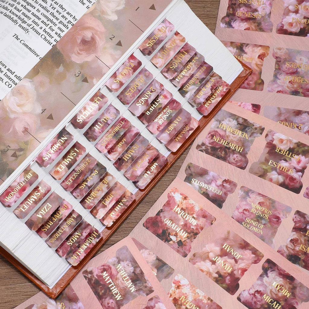 Open Bible with pink rose floral gold-foil index tabs lined along the page edge.