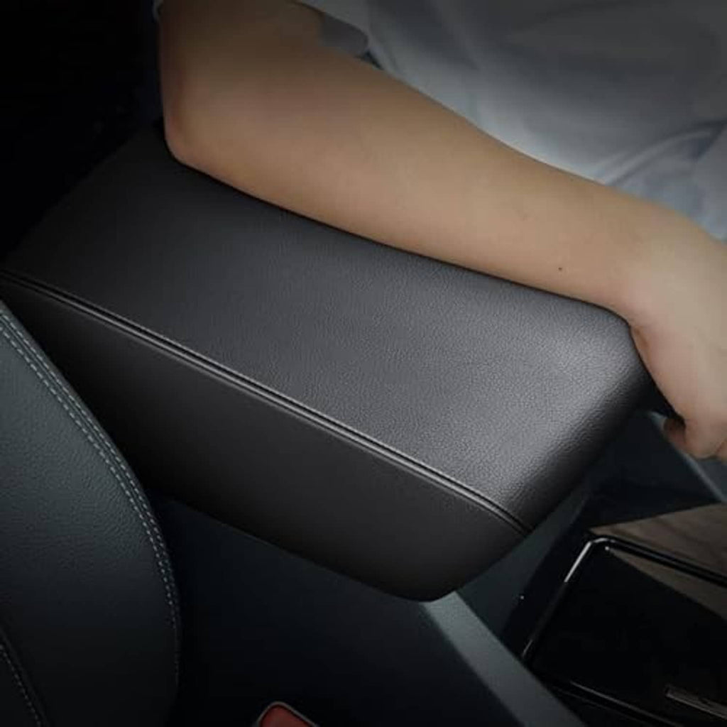 Black padded armrest with top seam, arm resting on the center console