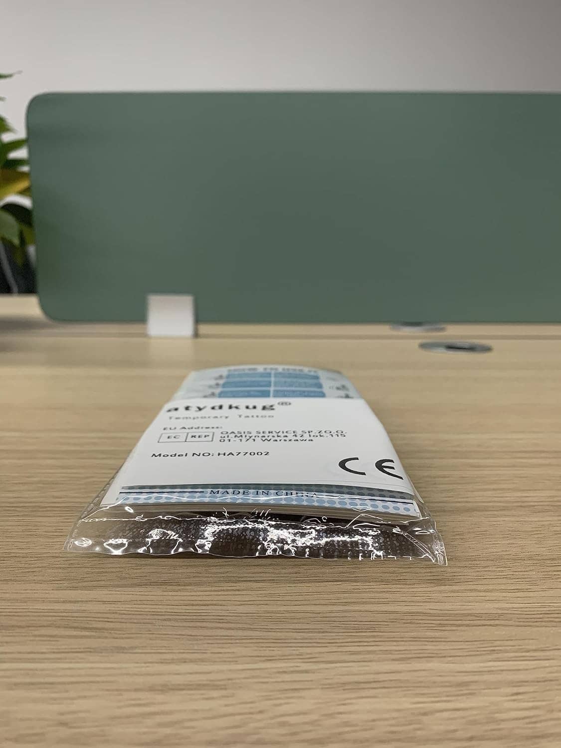 Sealed temporary tattoo instruction leaflet in clear plastic bag on a wooden desk