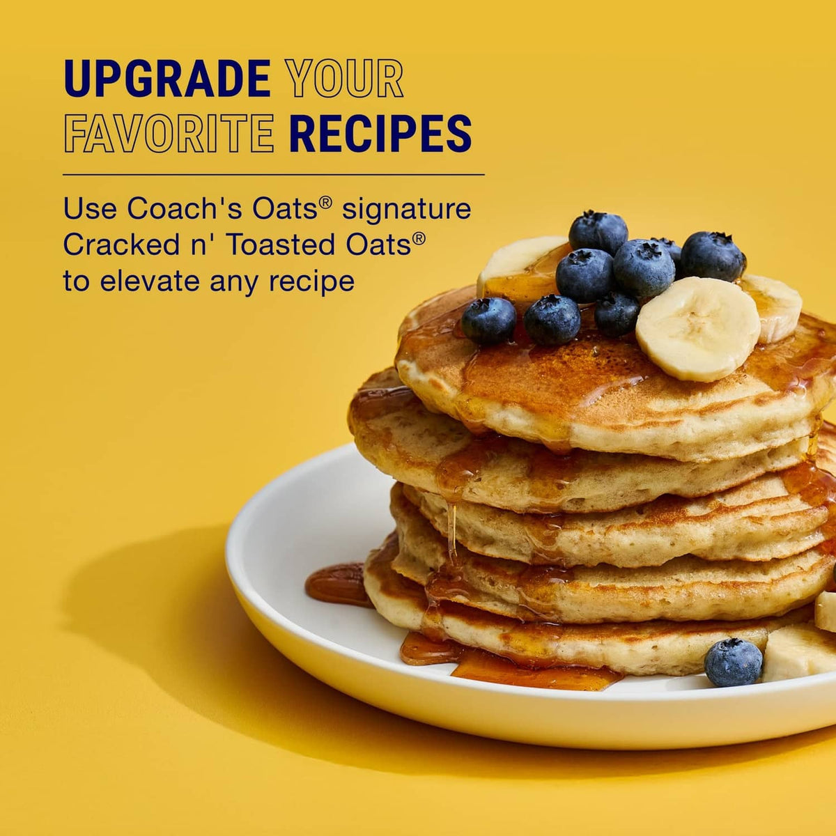 Stack of pancakes topped with banana slices and blueberries on a white plate
