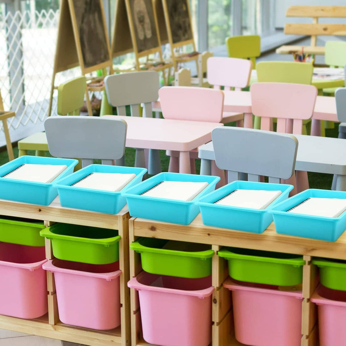 Stacked small object storage trays in teal, pink, and green on classroom shelves