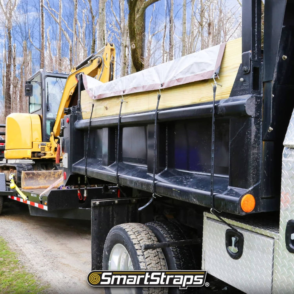 Black tarp cargo straps securing a covered load on a utility trailer