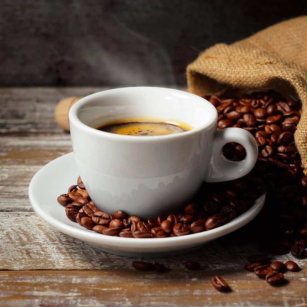 Coffee cup with crema and roasted coffee beans on a saucer