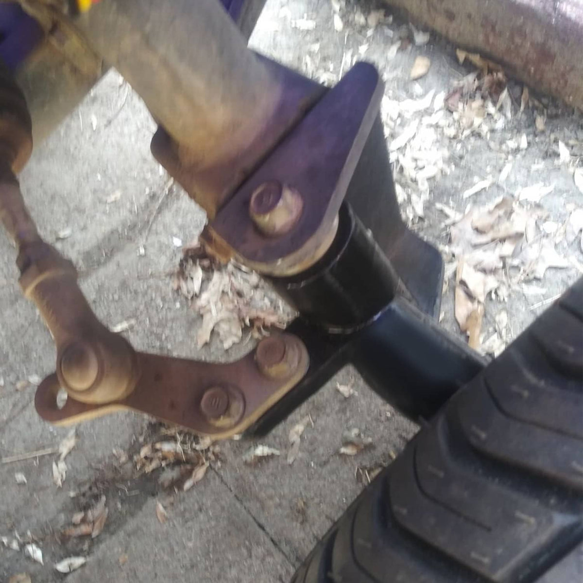 Installed black lift bracket with mounting bolts and linkage near front wheel area