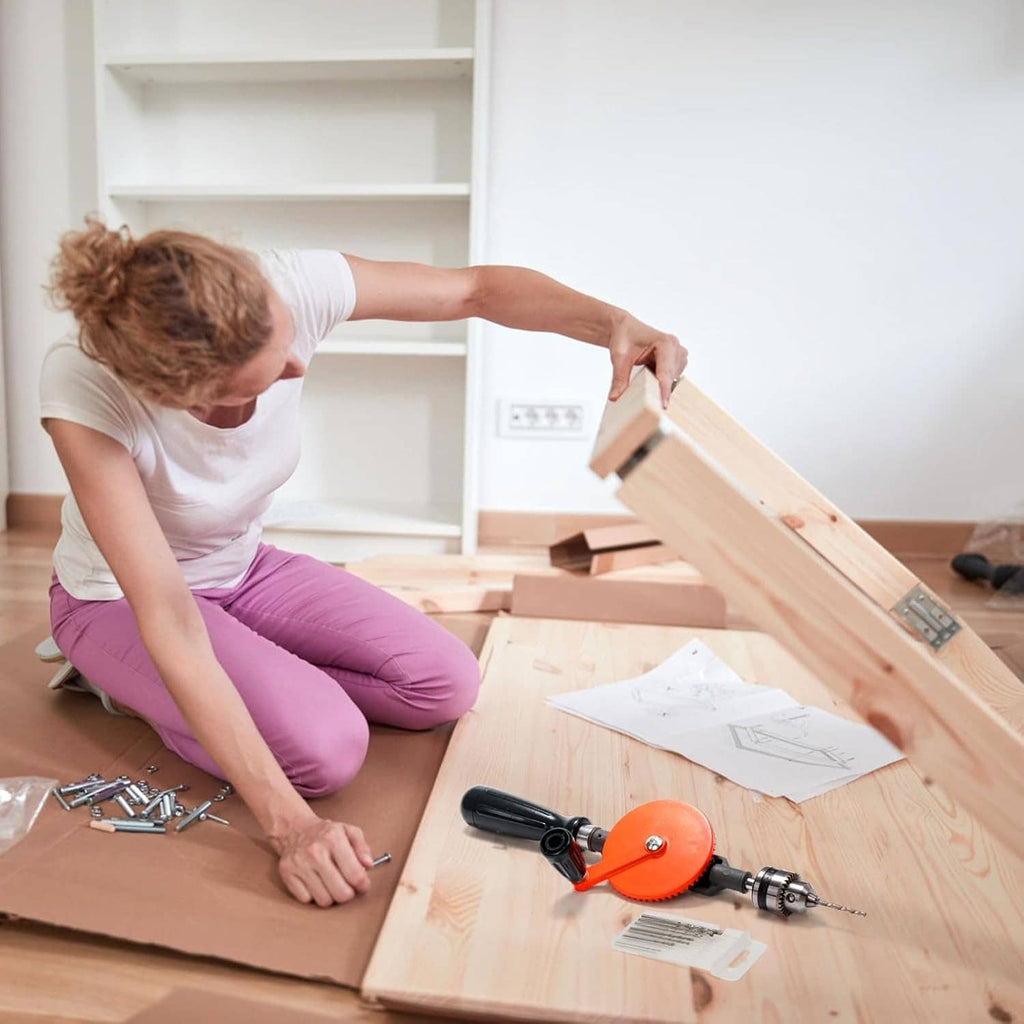 Manual hand drill with orange circular guard drilling through a wooden plank