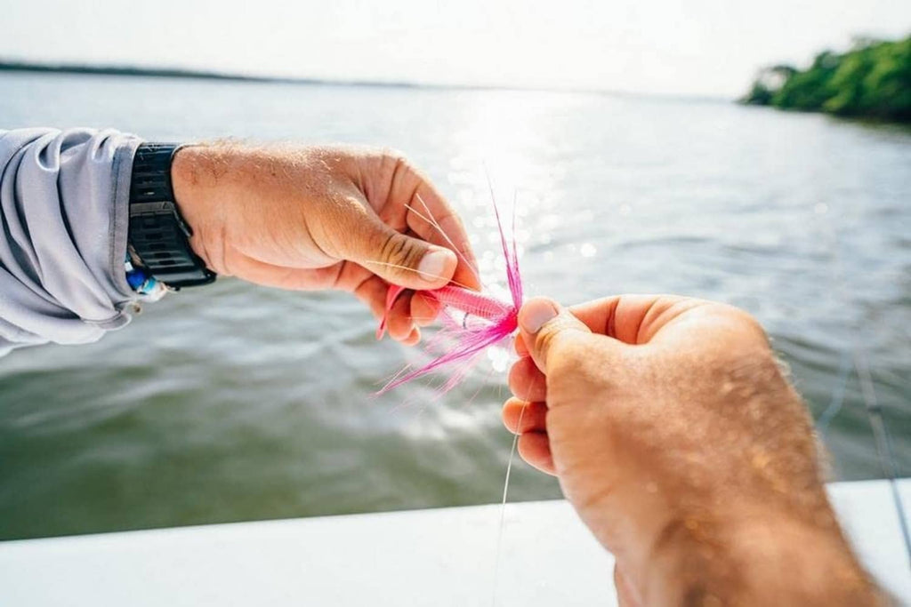 Pink soft bait lure in hands with hook and fishing line visible