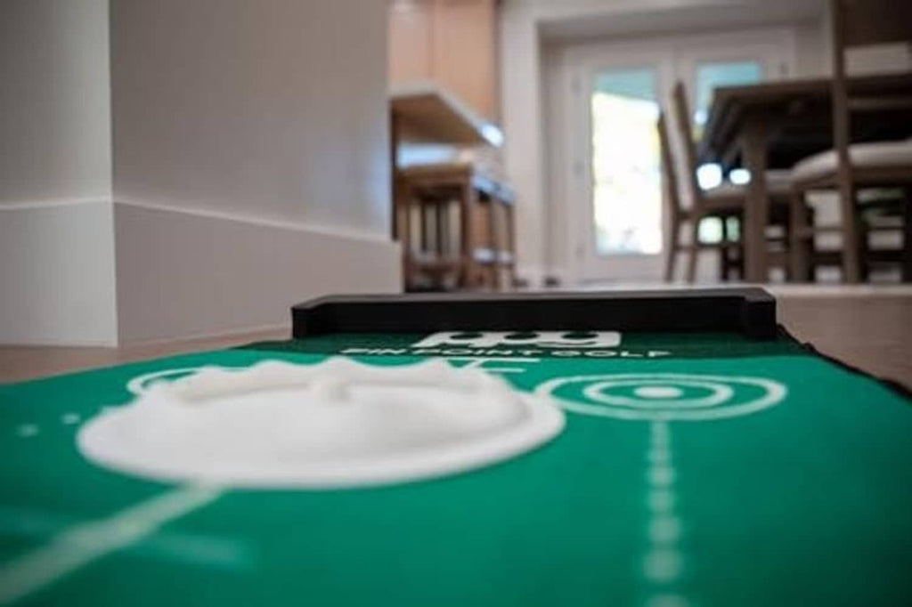 Green putting mat with white hole target graphic and black training cup