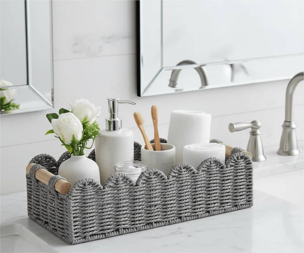 Grey woven storage basket with scalloped rim and wood handles, holding bath essentials.