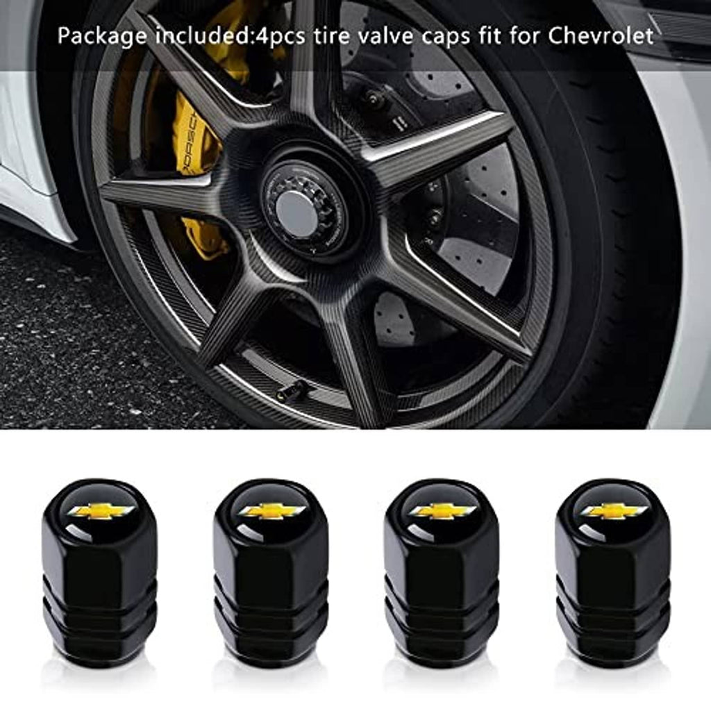 Four black valve stem caps with gold bowtie accents, near a car wheel