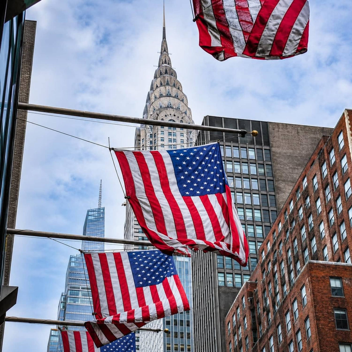 Several American flags on poles against a bright sky