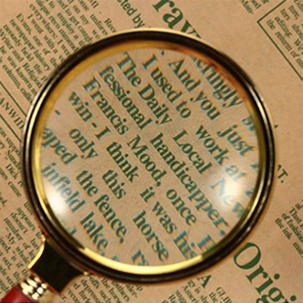 Magnifying glass magnifying text through round lens, gold rim and red handle