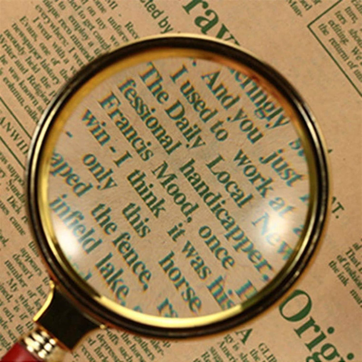 Magnifying glass magnifying text through round lens, gold rim and red handle
