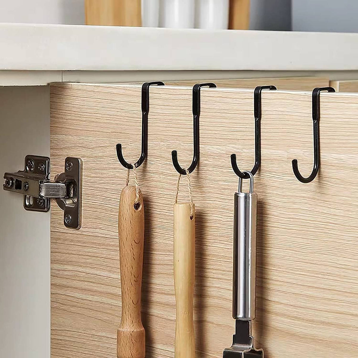 Black shower door hooks installed on cabinet door, holding hanging items
