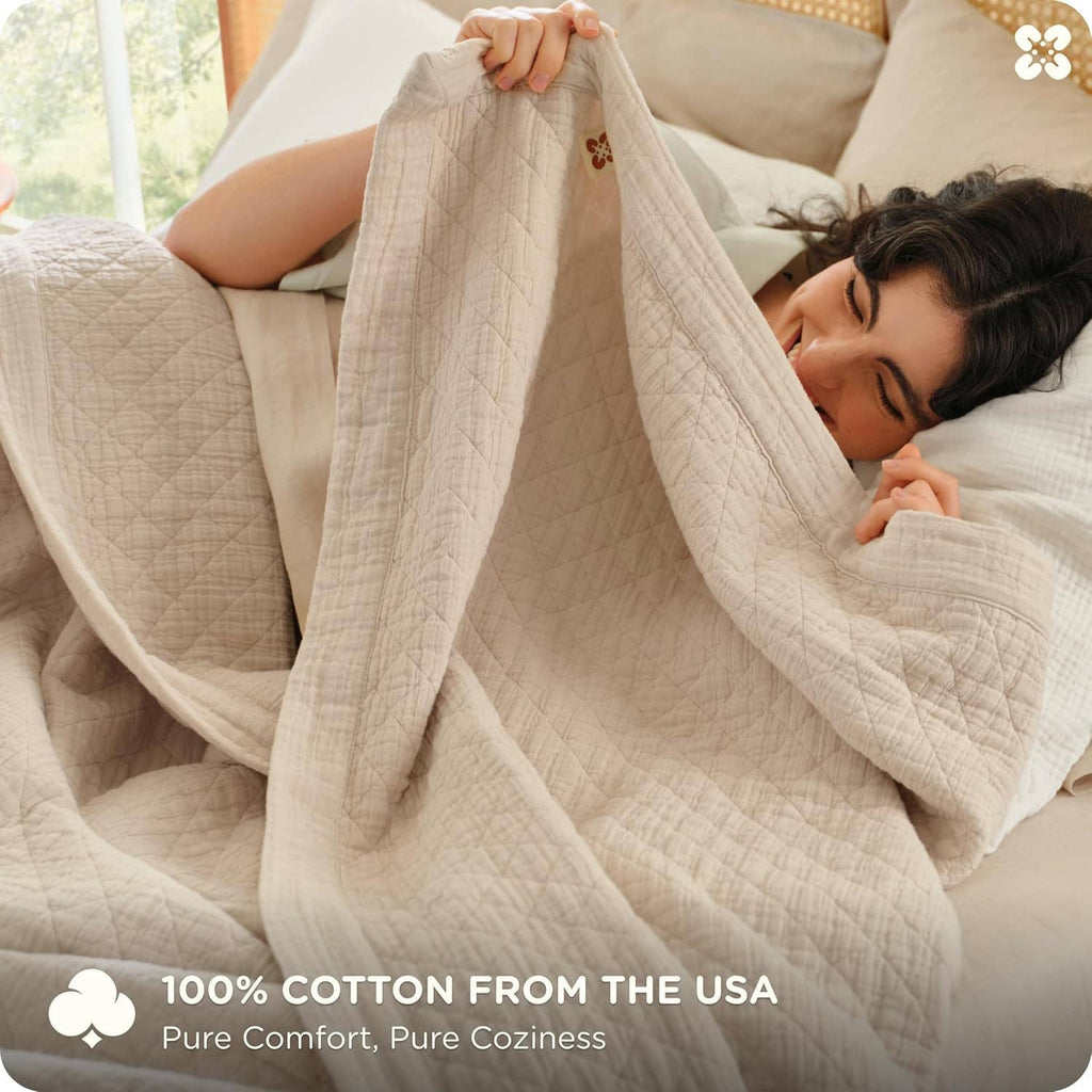 Cream cotton muslin blanket draped over two people on a bed, soft quilted weave
