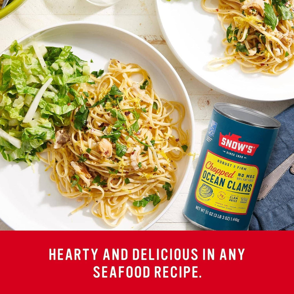 Canned chopped ocean clams beside spaghetti and salad in a meal scene