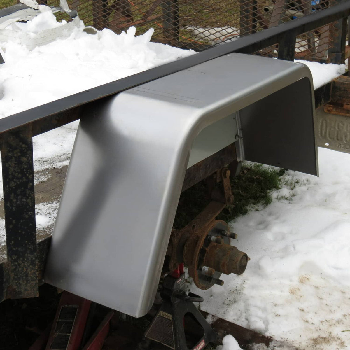 Installed trailer wheel fender, light gray metal cover with open inner support