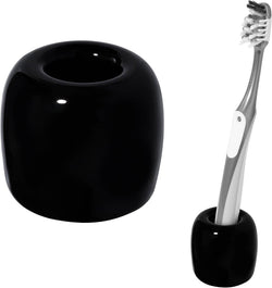 Black ceramic toothbrush holder with toothbrush standing in the round cup; smooth glossy finish.