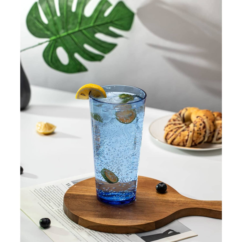 Blue hammered highball tumbler with ice, lemon slice, and olives on wooden board