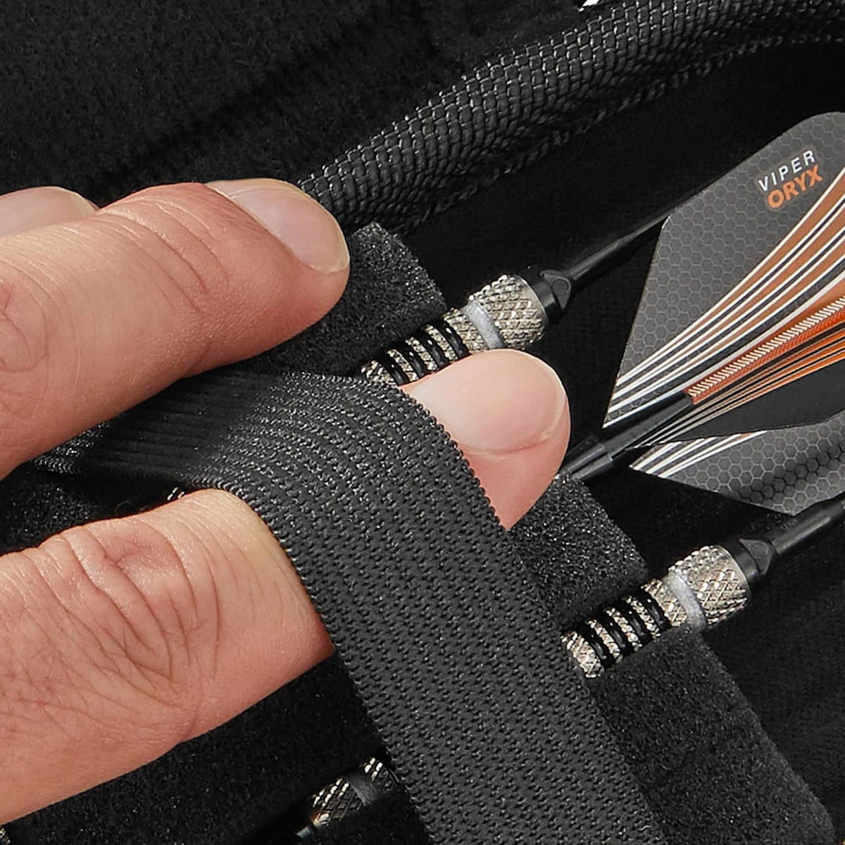 Close-up of black dart case divider holding metal dart shafts and grippy straps.