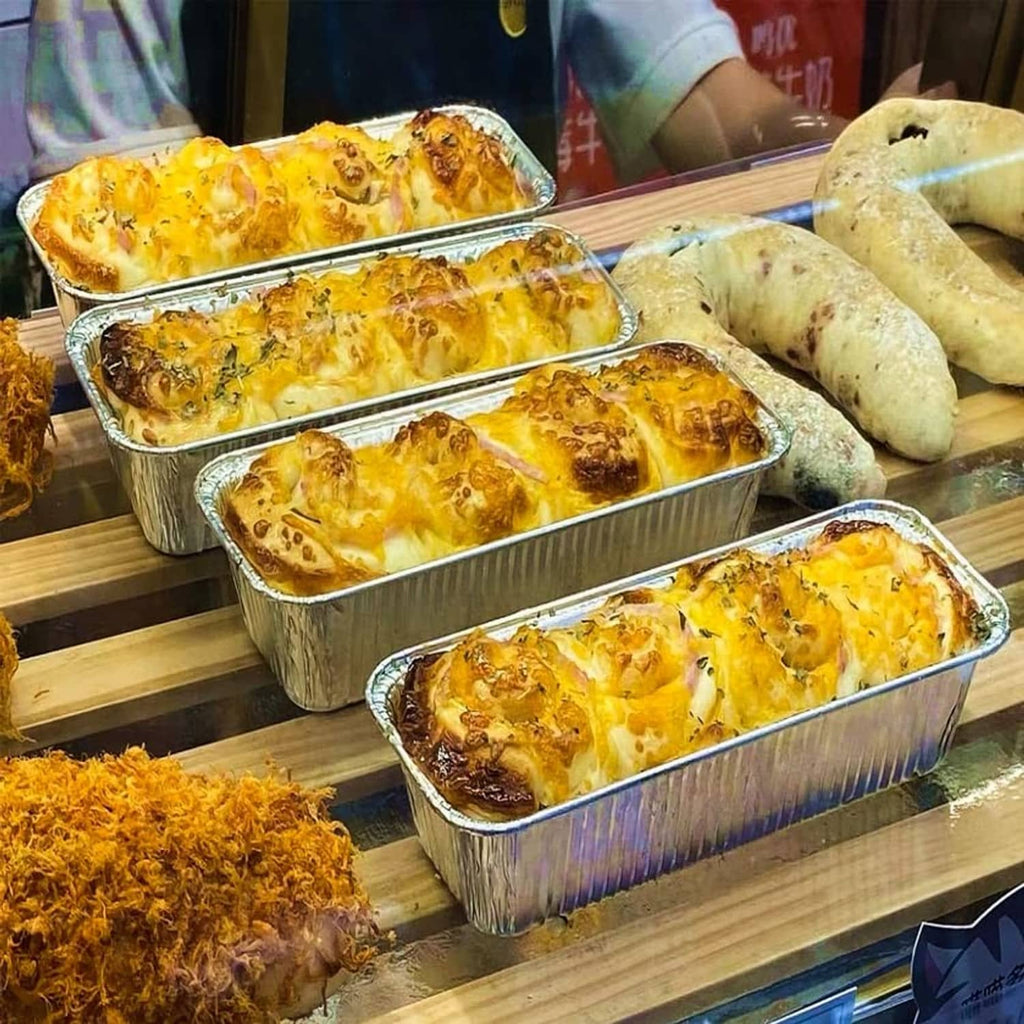 Aluminum mini loaf baking pans filled with baked loaves, foil rectangle trays