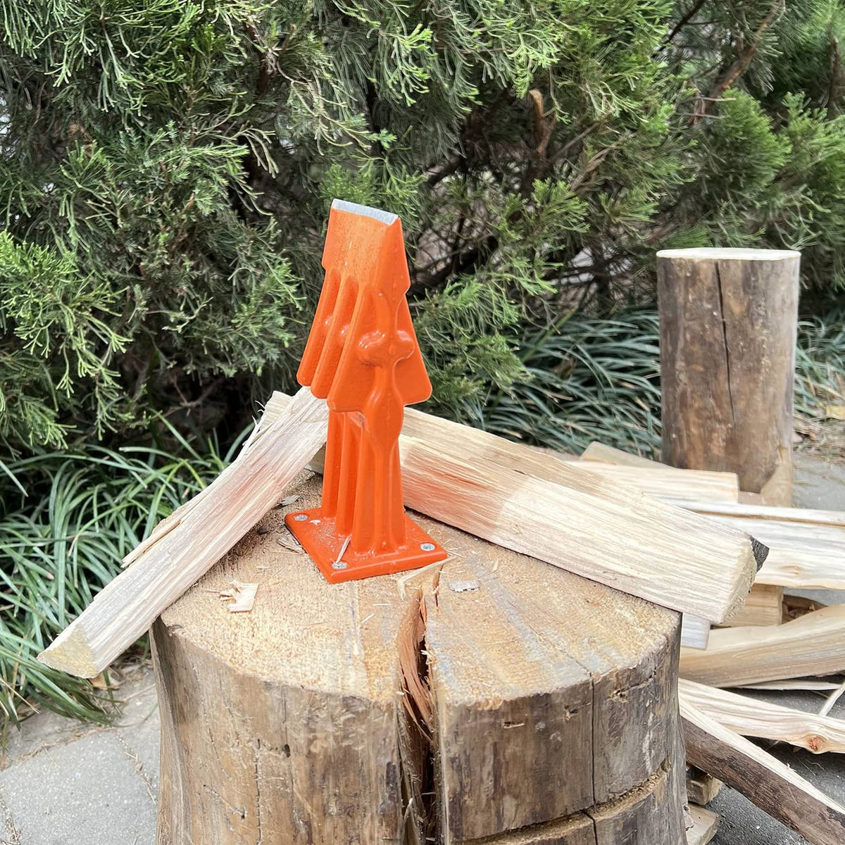 Orange log splitting wedge tool on stacked firewood logs