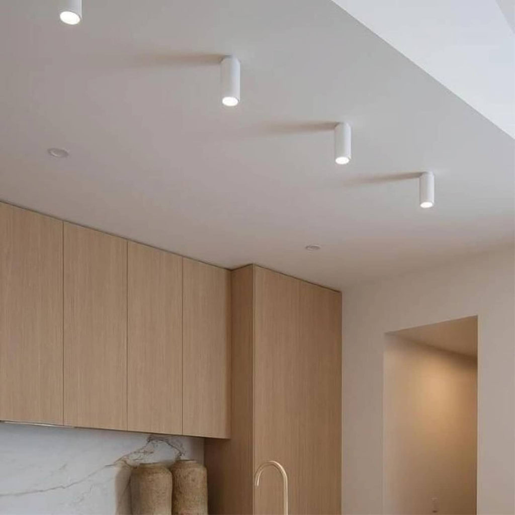 Ceiling spotlights with small cylindrical white housings in an indoor living space