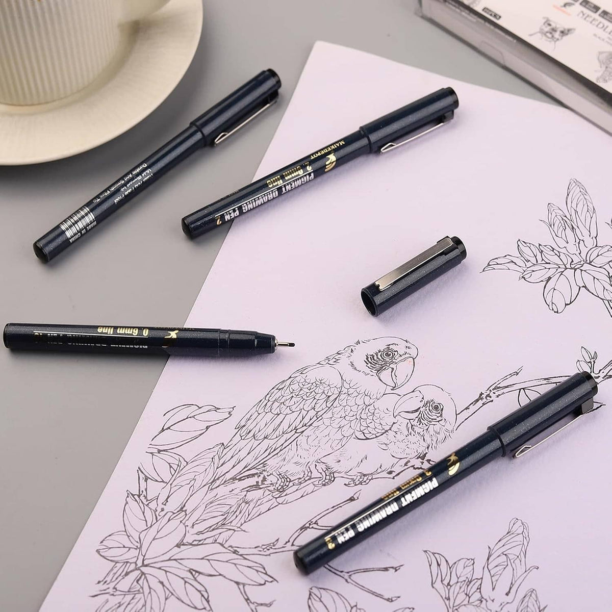 Needle drawing fineliner pens on sketch paper with bird and floral line art