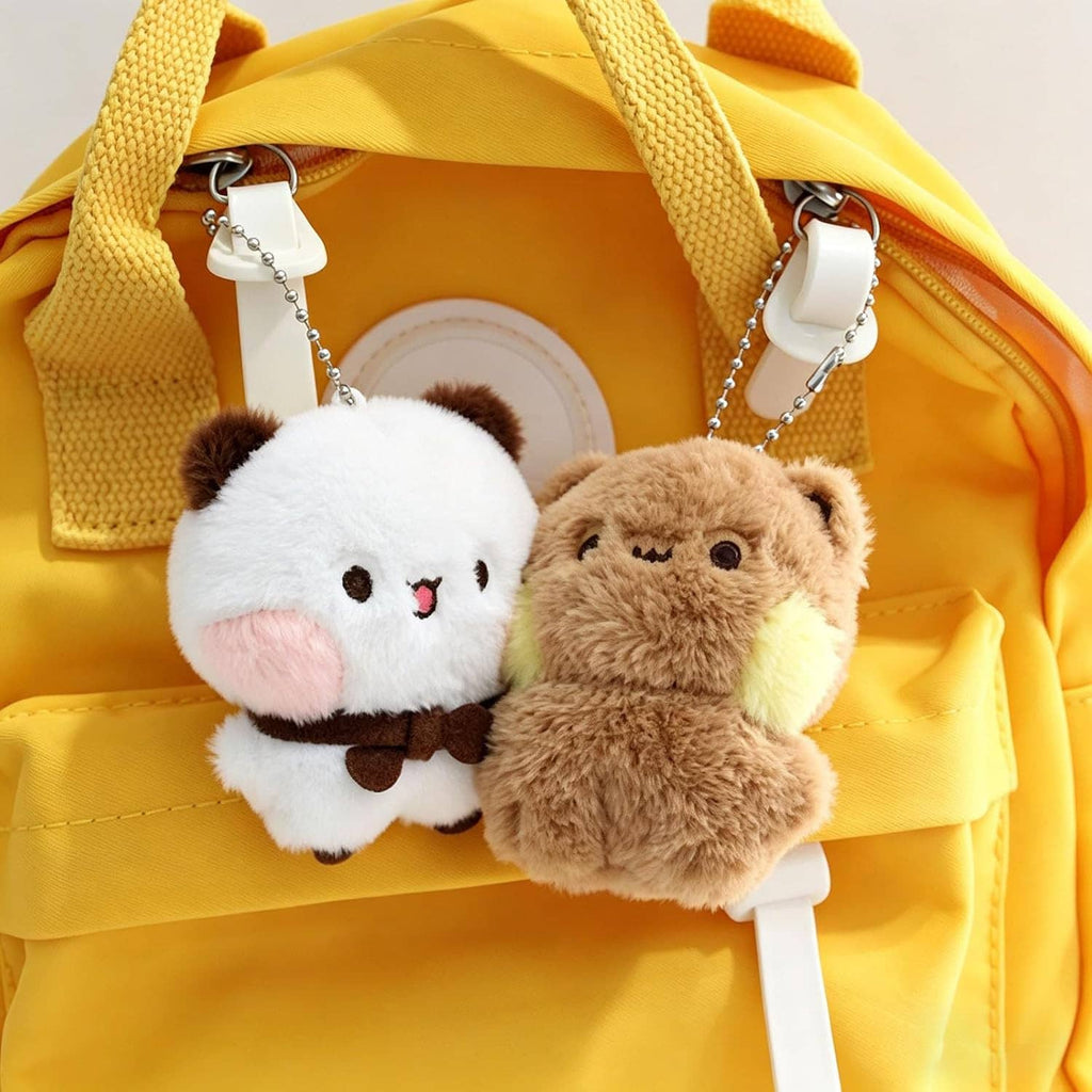 Plush bear keychains clipped to a yellow bag, white and tan bears with bead chains