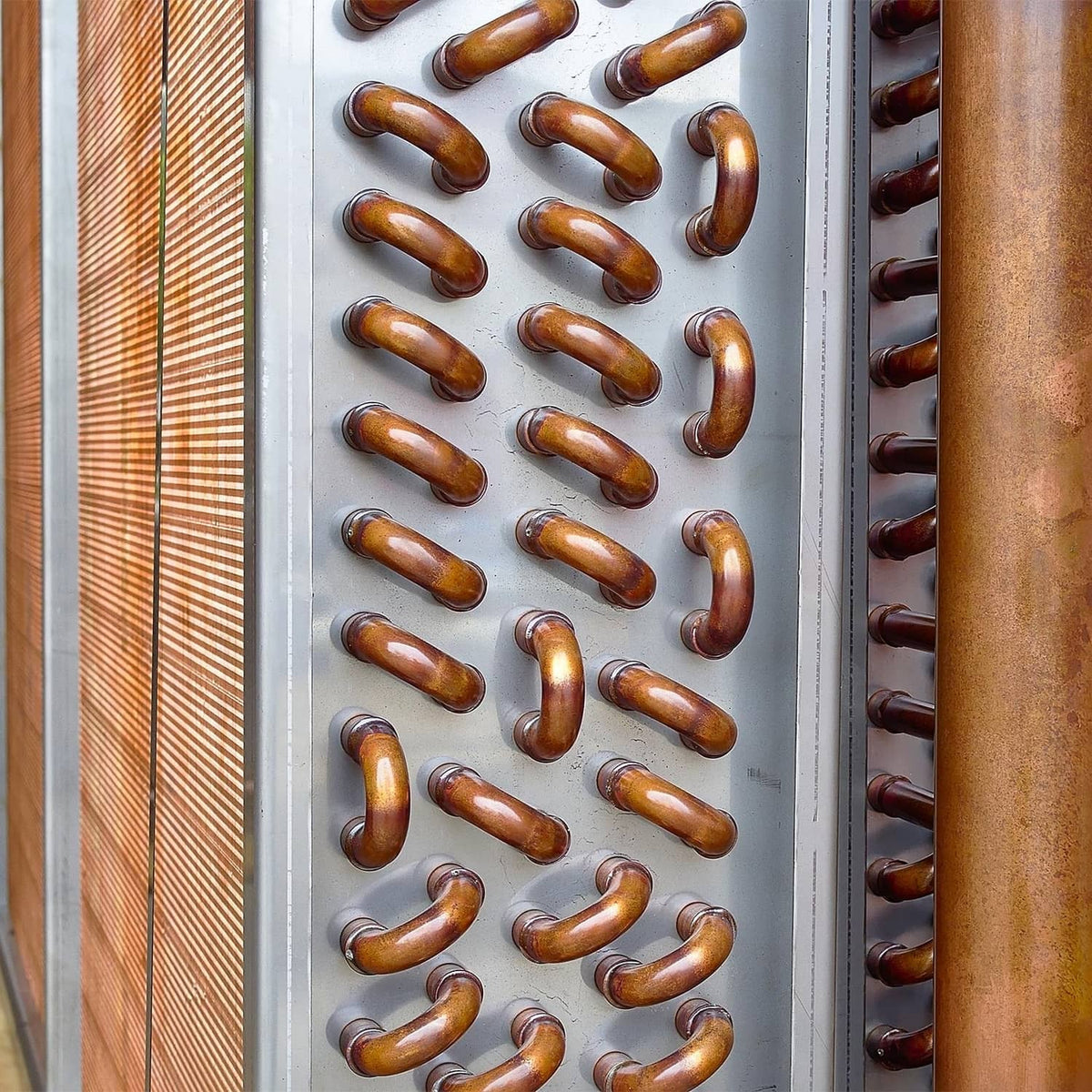 Copper elbow pipe fittings arranged in rows on a perforated panel