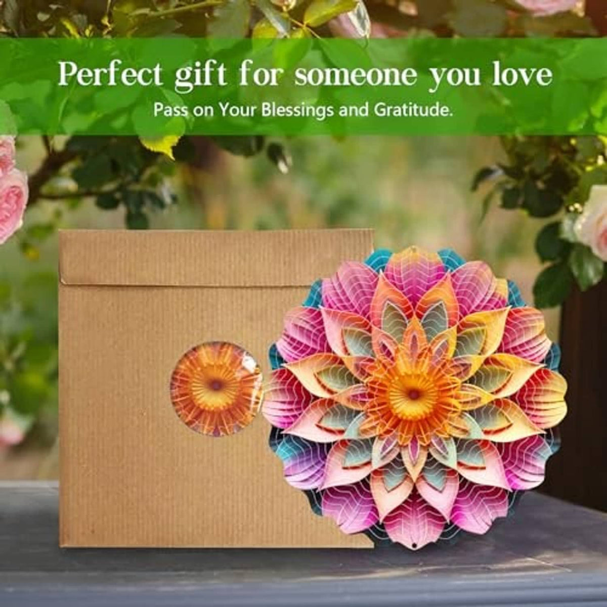 Metal mandala wind spinner with pink petals next to a cardboard gift box