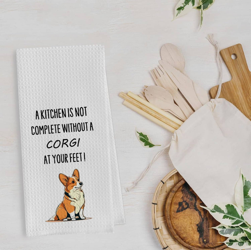 White waffle weave kitchen towel with corgi illustration and text: “A kitchen is not complete”.