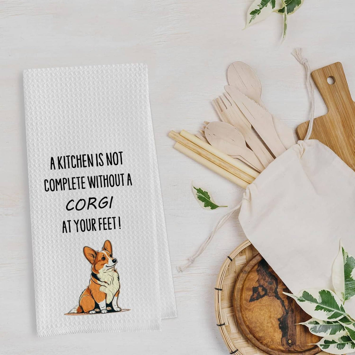 White waffle weave kitchen towel with corgi illustration and text: “A kitchen is not complete”.