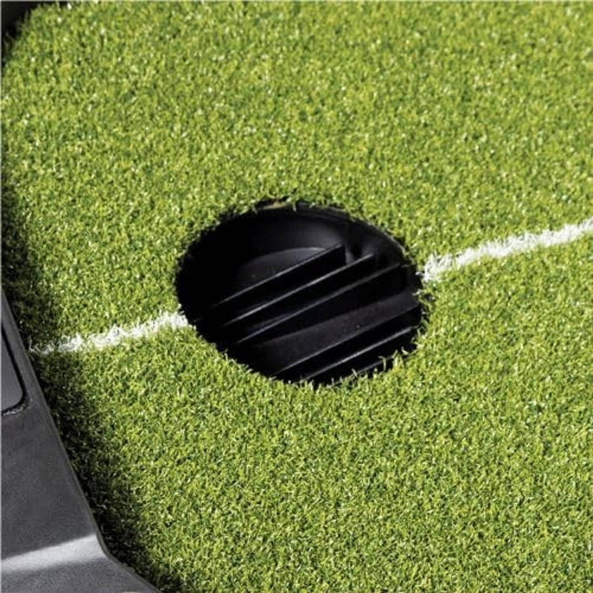 Black ball return insert centered in green artificial turf with white line