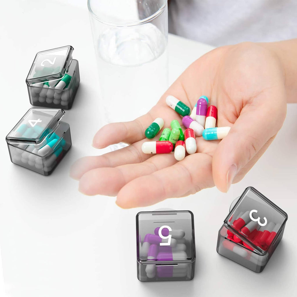 Pill organizer box with open trays and mixed pills in individual daily slots